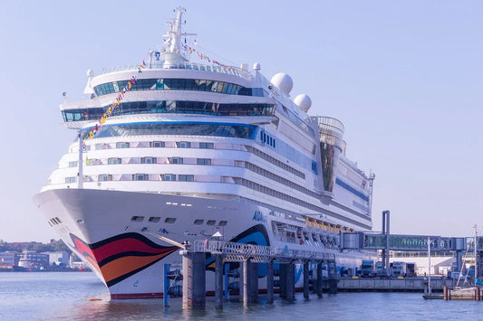 Large AIDA cruise ship docked at port with gangway and calm water under clear sky