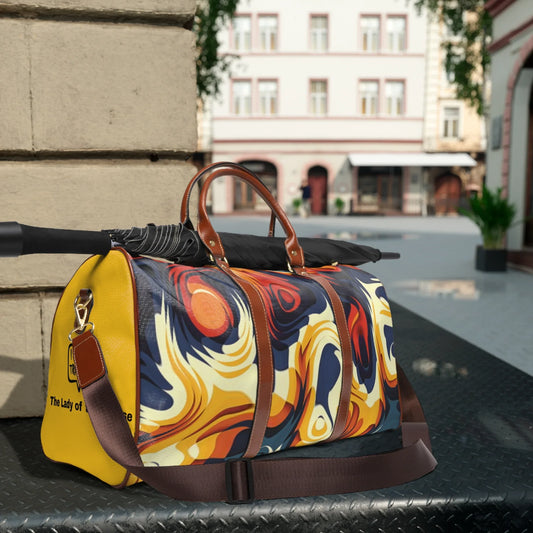 Colorful marbled pattern travel duffel bag with brown leather handles and a black umbrella on top outdoors