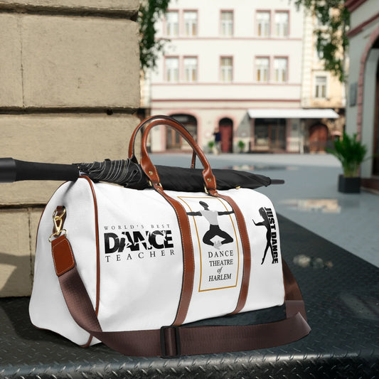 White dance duffel bag with brown straps, black umbrella, and dance-themed prints in city street setting