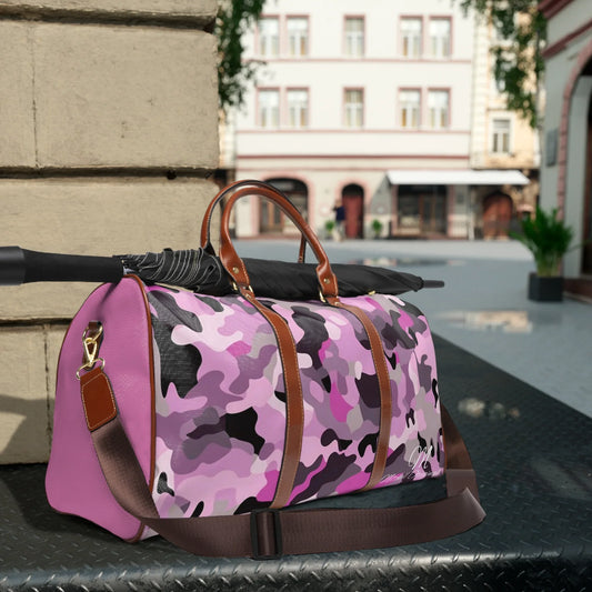 Pink and purple camouflage duffel bag with brown leather straps and black umbrella on metal surface outdoors
