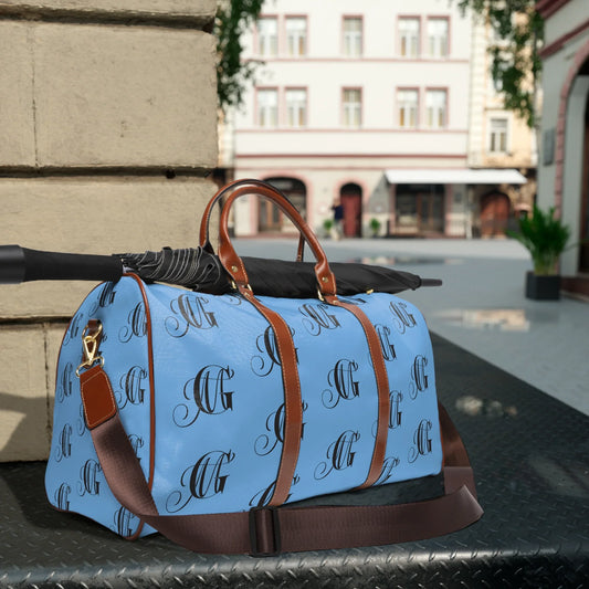 Blue and brown leather duffel bag with monogram pattern on outdoor metal table with black umbrella
